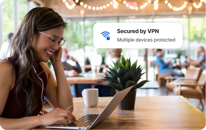 Femme dans un café riant devant l'écran d'un ordinateur portable